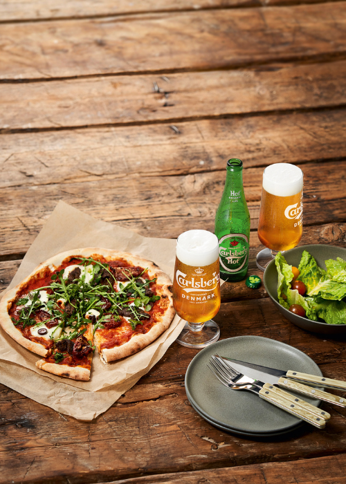 Öl och cider serverade tillsammans med pizza på restaurangbord